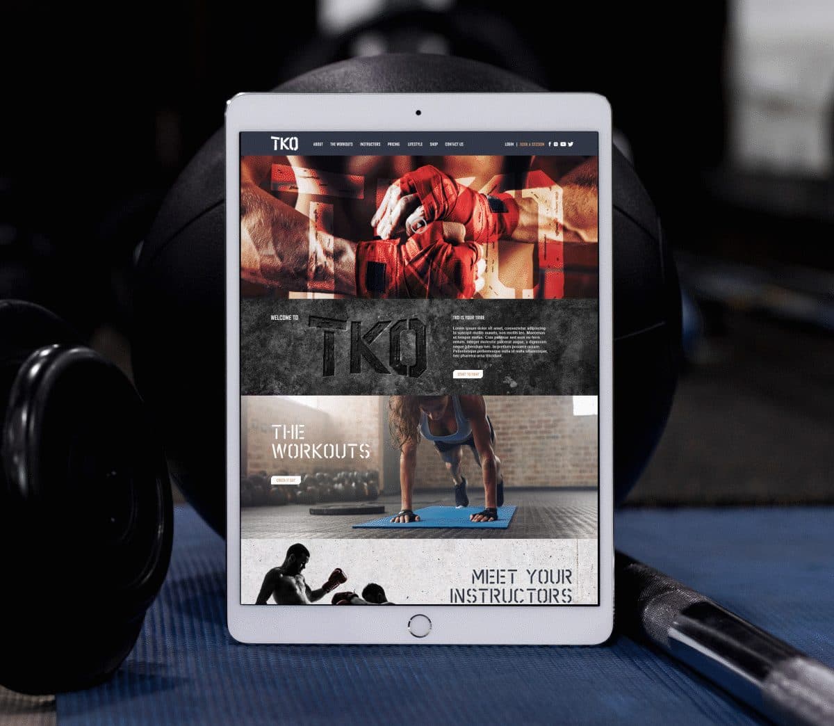 Tablet on a gym mat displaying a fitness website with bold 'TKO' branding and workout sections visible on screen